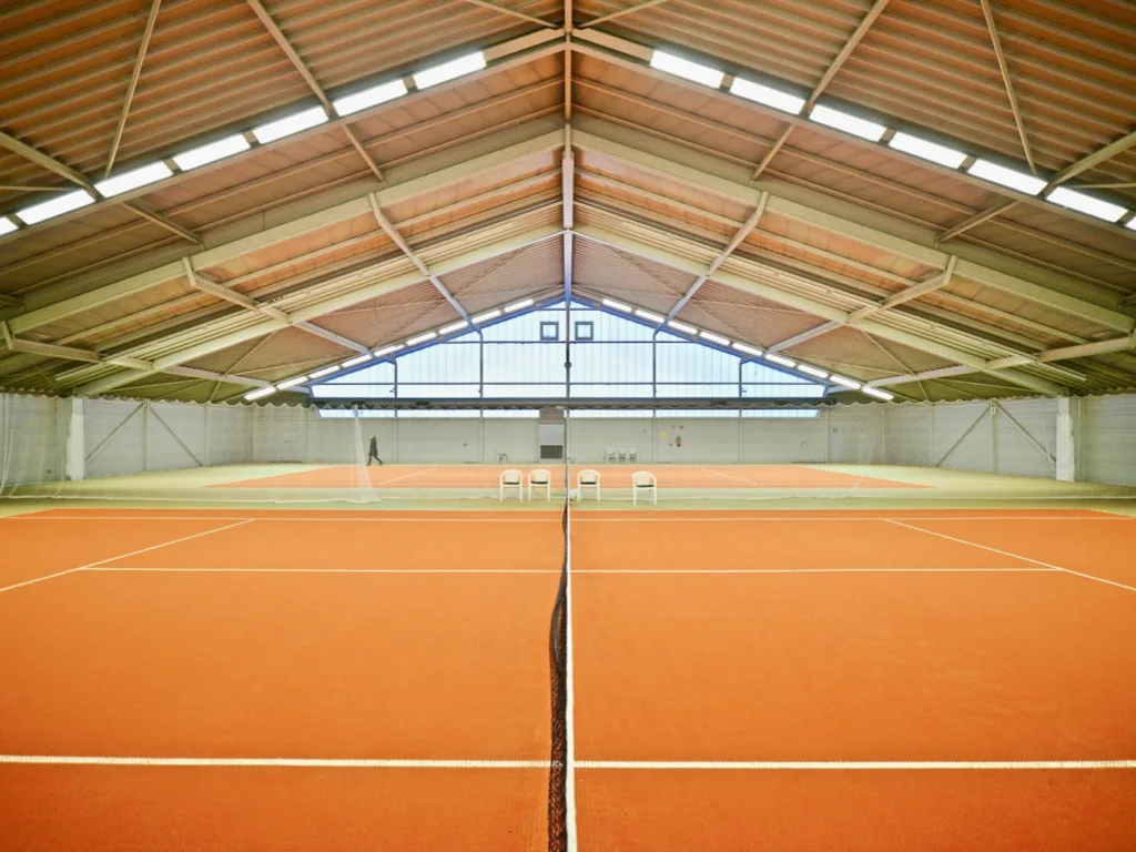 TRS2554RSH – En exploitation comme tennis couvert : portiques bi-articulés de grande portée, pannes et bac acier au-dessus des courts.